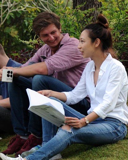 Two smiling students sitting on the grass
